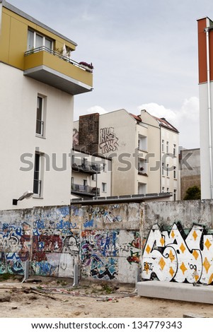 BERLIN - JUN 10: Wide angle view of graffiti covered remains of the berlin wall embedded within the walls of the buildings behind it, in Bernauer strasse on June 10 2012 in Berlin, Germany.
