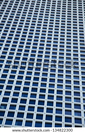 A large amount of identical square windows of a skyscraper. Shot from a low angle with a slight tilt.