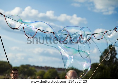 BERLIN - JUN 10: Unidentified senior man playing giant bubble wand game making bubbles outdoors on a sunny day at Mauerpark on June 10 2012 in Berlin, Germany.