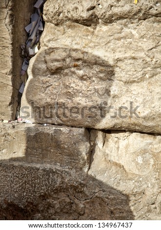 The shadow of an orthodox Jewish man on the sacred Wailing Wall in the old city of Jerusalem, Israel. Letters with wishes and pleading to god can be seen in the large crack between the ancient stones.