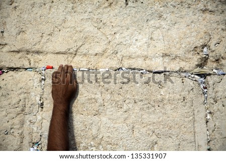 The left hand of an adult male placing a note in the cracks of the holy Western Wall in the old city of Jerusalem, Israel.