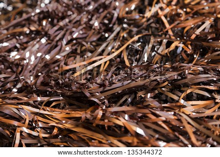 Close-up view of entangled magnetic tapes in various hues of brown, taken off (many) audio cassettes. Shallow depth of field, focus on foreground.