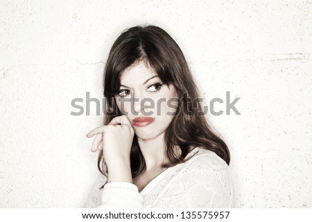 Portrait of a beautiful young woman with her big eyes glancing to her right, looking rather displeased. She seems to be very envious and displeased with someone/something off frame.