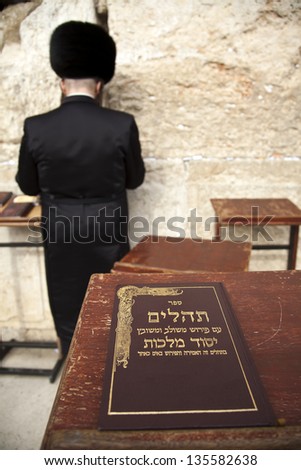 JERUSALEM - MAY 21:The biblical book of psalms resting on a pedetal in front of the wailing wall. An orthodox Jewish male praying in the background on May 21 2010 in Jerusalem, Israel.