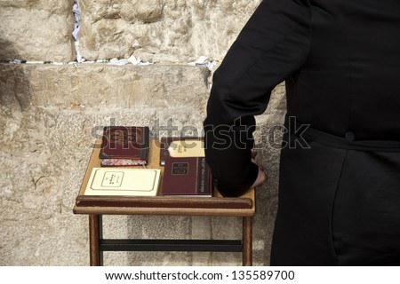 The hand of an orthodox Jewish man resting on a pedestal with four editions of the biblical book of psalms. Shot at the wailing wall in the old city of Jerusalem, Israel.
