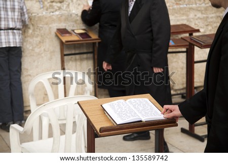 JERUSALEM- CIRCA 2012: An Orthodox Jewish man\'s hand on a prayer book opened on one of the pages of the morning prayer. Shot in the western wall in the old city of Jerusalem, Israel, circa 2012.
