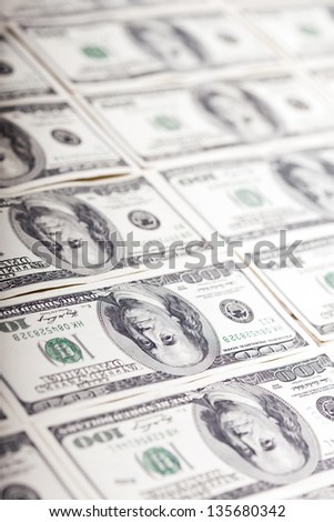 A large quantity of 100 US$ money notes lined up in a vertical row. Very shallow depth of field.