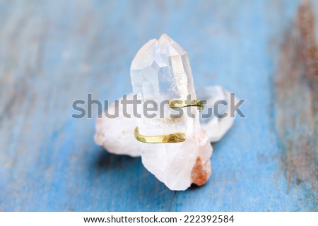 Still life of a hand made tribal ethnic ring resting on a crystal on light blue background.