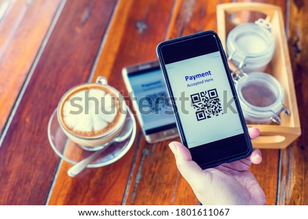 Customer hand using smart phone to scan QR code tag on another smart with coffee in coffee shop or restaurant to accepted generate digital pay without money. Qr code payment concept.
