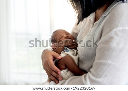 Portrait images of half African half Thai, 12-day-old baby newborn son, sleeping with his mother being held, to family and infant newborn concept.