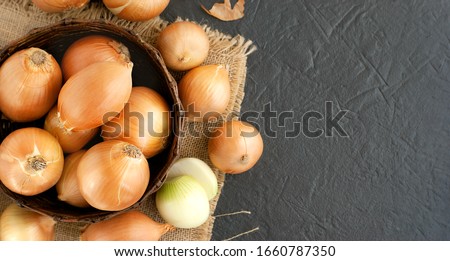 A lot of onions in a basket on a textural background.
Vegetables in a basket in the form of onions. Harvest onions on burlap.