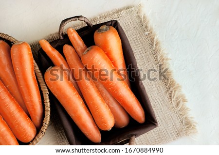 A lot of carrots in a basket on burlap. Vegetables in the form of carrots. Carrots for diet food. A lot of carrots in two baskets.