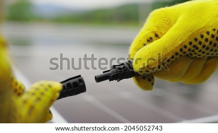 Solar Station Equipment. Connecting wires of solar panels at a solar farm. Engineers connect electrical system outdoors on a background of solar panels. Worker in protective gloves connects wire Photo stock © 