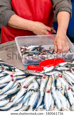 man cleaning fresh caught saltwater fishes and preparing them on a tablet