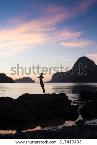 Man with his hands up at the sunset time