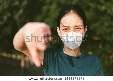 Coronavirus and Air pollution pm2.5 concept.Woman wearing mask for protect pm2.5 and show thumb doen gesture for stop corona virus outbreak.Wuhan coronavirus and epidemic virus symptoms. Stockfoto © 