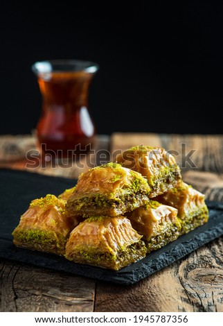 BAKLAVA. Traditional Turkish Desserts Baklava with Turkish Tea. Crispy pistachio baklava on black plate.