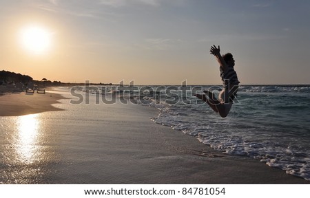 Happy man jumping over sea. Sand beach at sunset. Cuba vacation.