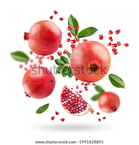 A ripe pomegranate with seeds and leaves flying in the air. Background with pomegranate fruit. Pomegranate fruit on a white background.