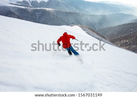 Image, Stock Photo Skier with red jacket and green backpack in icy snowy landscape walks on lonely ski track on way to mountain in evening light