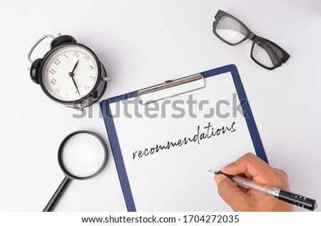 Top view of clock, magnifying glass and note written with Recommendations on white background. Selective focus. Foto d'archivio © 