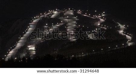 a busy ski mountain at night with many illuminated trails