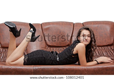 Pretty brunette in black dress laying on brown sofa