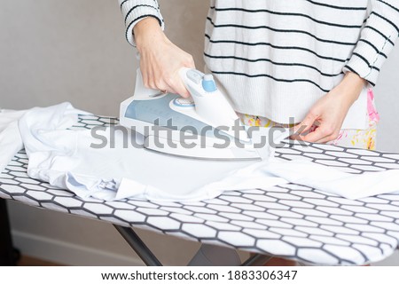 Woman is ironing clothes. The girl holds an iron on an ironing board with a ferry and irons things. Cleaning service of the apartment