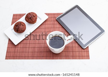 Chocolate chips Muffins with  a cup of coffee meanwhile using the tablet PC.