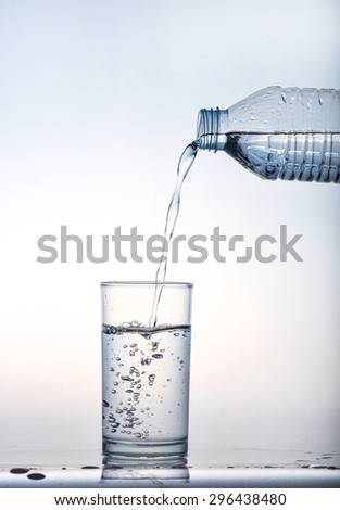 Pouring water from bottle into glass on blue background, water glass, Water pour into glass