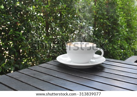 white cup of hot coffee on wooden table in coffee shop,white cup of hot coffee on wooden table on green natural background
