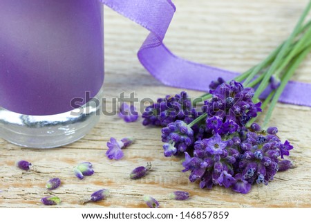 bottle of lavender oil with purple ribbon and lavender flowers on a wooden background