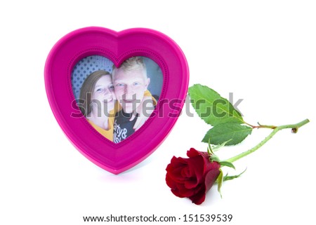 smiling couple in a heart photo frame with a red flower in front of it isolated on white