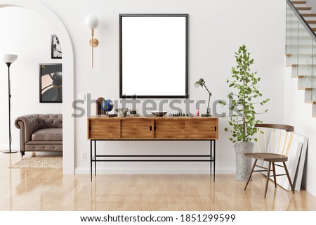 Stylish and eclectic dining room interior with mock up poster map, sharing table design chairs, gold pedant lamp and elegant sofa in second space. White walls, wooden parquet. Tropical leafs in vase.
