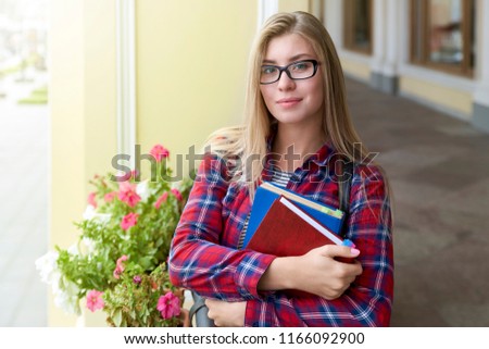 stock-photo-young-attractive-student-girl-in-plaid-shirt-poses-for-a-portrait-on-the-background-of-the-campus-1166092900.jpg