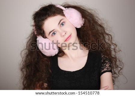 Quirky girl with ear muffs. Beauty portrait of a gorgeous young woman with big hair, ear muffs, & a sense of humor.  Processed from RAW, detailed retouching.
