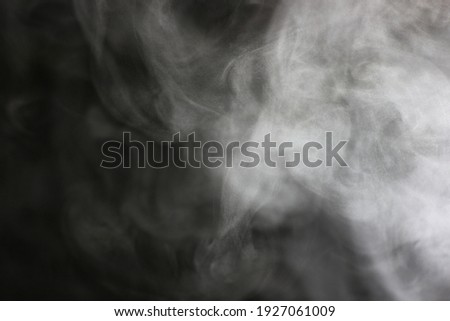 steam in a beam of light from a boiling kettle on a dark background
