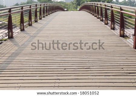 The wood bridge with wood planks and iron railings.