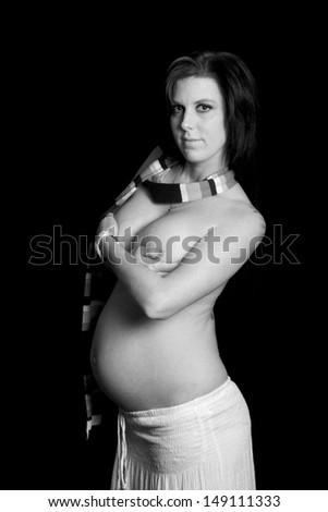 Pregnant woman with scarf and white skirt against black background in black and white