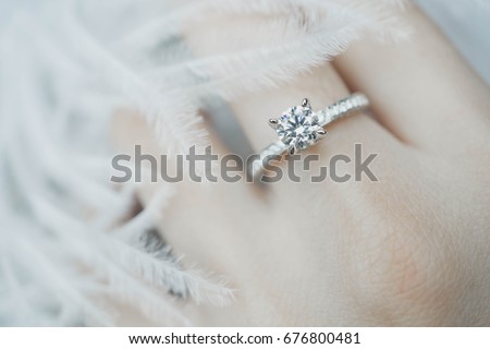 Close up of elegant diamond ring on the finger with feather and gray Scarf background. Diamond ring. Imagine de stoc © 