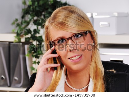 attractive young woman is calling with a mobile phone in her office