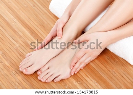 Beautiful female hands and feet with white towel on wooden floor