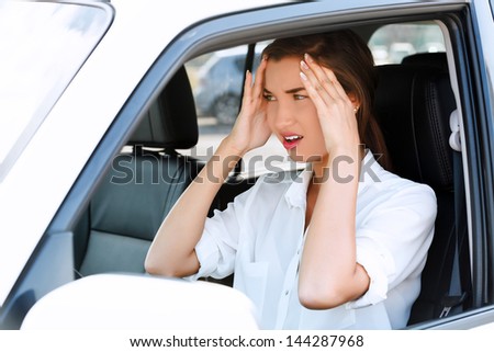 Troubles on the road, girl touches her forehead by hands while in a car