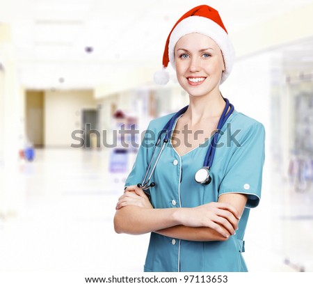 Smiling female medical doctor wearing red hat in a hall of a hospital. Christmas time concept.