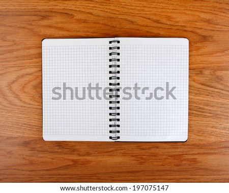 Notepad with a spiral binding and checkered sheets on a wooden background