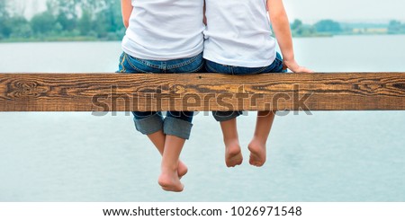 Two brothers swung their legs from the wooden pier .Family vacation on the lake. Сток-фото © 