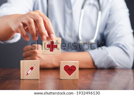 A doctor holding wooden dice with icons of health and doctors in his hands. Close-up photo. Space for text. Concept of doctor work in maintaining human health