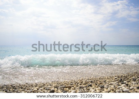 Waves crashing on rocks. blue waves, sand beach and blue sky. Greece, the island of Lefkada, Yialos Beach, Gialos. one rock in the waves