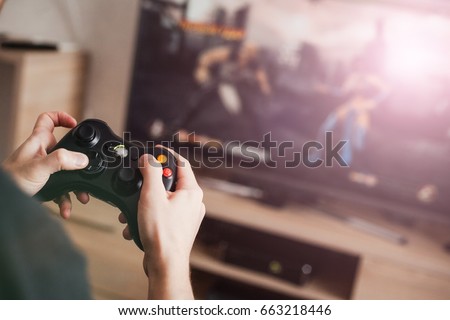 Similar – Image, Stock Photo Man playing video game at home. Gamer playing online in dark room lit by neon lights. Competition and having fun