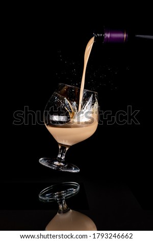 Cream liqueur pouring into floating glass with splash on black background with reflection Сток-фото © 